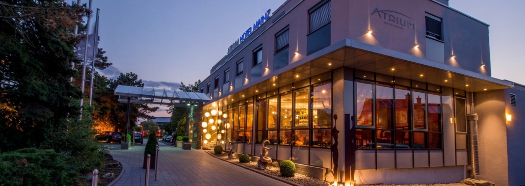 Atrium Hotel Mainz - Veranstaltungsort Abendliche Außenansicht des Atrium Hotel Mainz mit beleuchtetem Eingangsbereich.